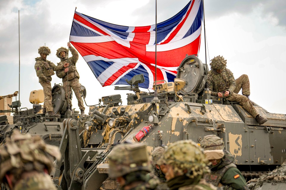 British soldiers raising the Union Jack on a military vehicle during a NATO exercise.