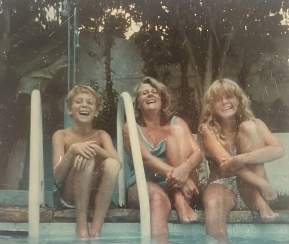 Photo of a mother and her two children smiling by a pool.
