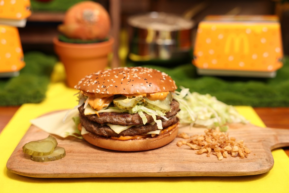 Double cheeseburger on a wooden board with pickles and fried onions.