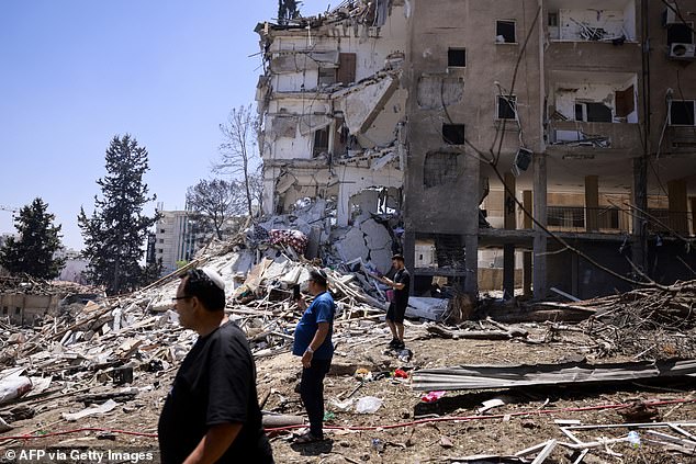 Residents check the destruction following an overnight Iranian missile strike in Rohovot in central Israel on June 15, 2025. Iran struck Israel early on June 15, with barrages of missiles after a massive onslaught targeted the Islamic republic's nuclear, military and oil facilities, and killed several top generals
