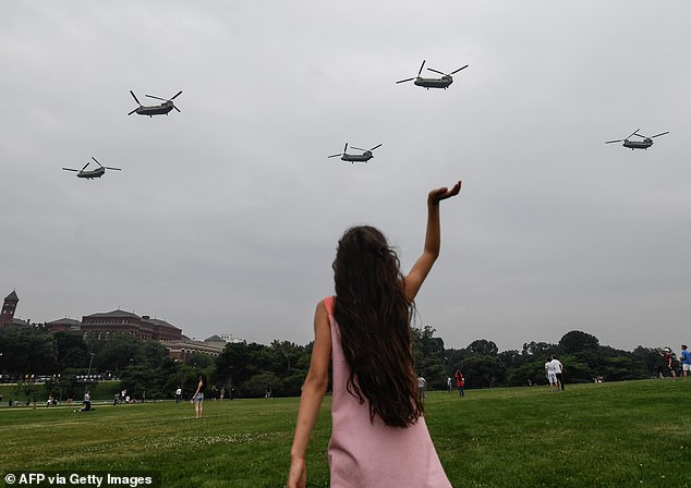 A girl waves at a squad of helicopters as they do a flyover during the Army 250th Anniversary Parade in Washington, DC, on June 14, 2025