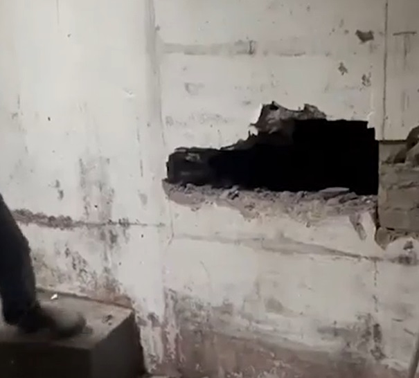 A hole knocked in a plaster wall revealing a tunnel.