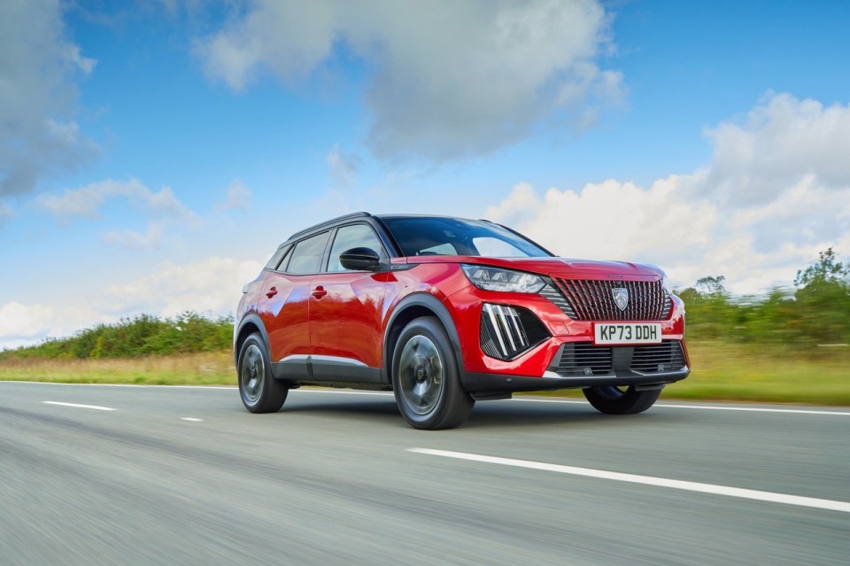 Red Peugeot 2008 driving on a road.