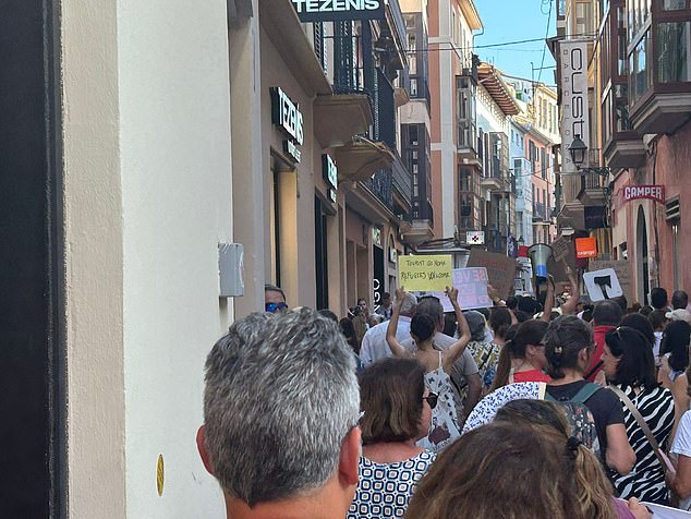 A woman holds up a placard reading: 'tourists go home¿ refugees welcome'