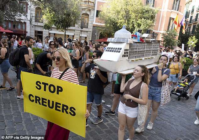 Demonstrators hold a cardboard cruise boat during the protest in Palma de Mallorca