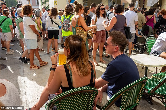 Tourists continue with their meals and drinks as the anti tourism protesters go by in the Old Town in Ibiza on Sunday evening