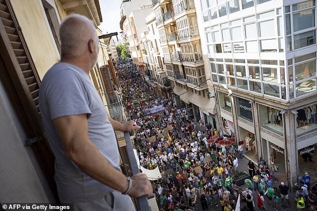 A man watches on from his balcony as protesters line the streets below