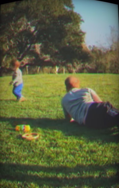 A toddler and a man in a grassy field.