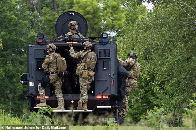 The military-style convey traveled in armored vehicles with rooftop snipers, but as of 7pm, the fugitive was still at-large