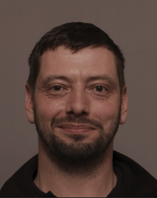 Mugshot of a man with short brown hair and a beard.