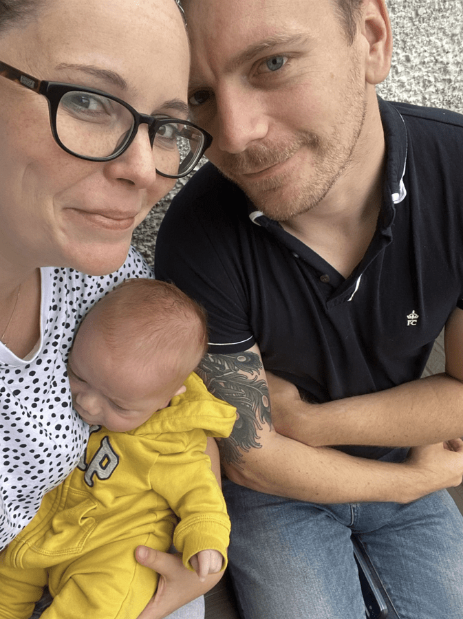 A family selfie: parents holding their newborn baby.
