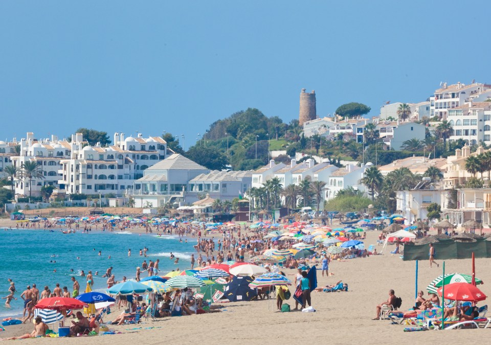 Butibamba beach in La Cala de Mijas, Spain, crowded with people and umbrellas.