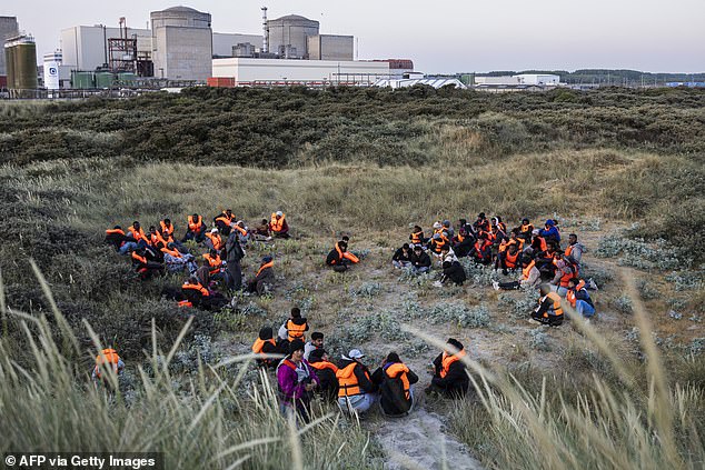 Migrants hide in the dunes as they wait to board a smuggler's boat in an attempt to cross the English Channel