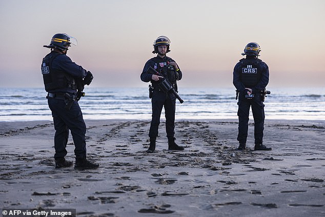 French Police stood on the beach in an attempt to prevent migrants making the crossing