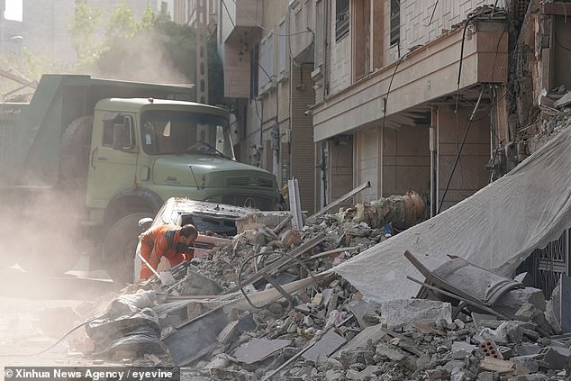 A rescuer attempts to remove debris of buildings damaged during Israeli strikes