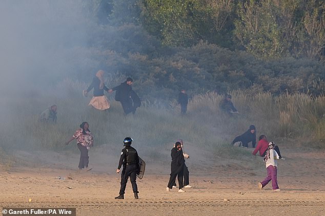 People thought to be migrants emerge from bushes on a beach in Gravelines, France, after French authorities had fired tear gas