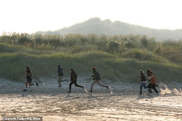 Migrants today waited for a 'taxi boat' dinghy they are paying typically £1,500 each to ferry them across the Channel