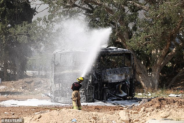 A firefighter works to extinguish a destroyed bus just outside Tel Aviv
