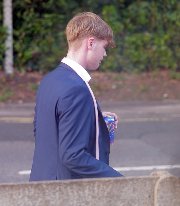 A young man wearing a blue suit seen with a can of Foster's lager