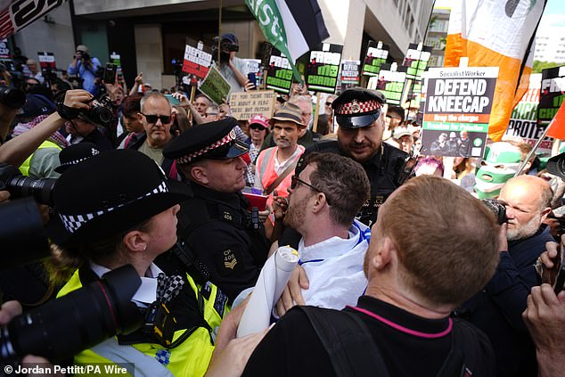 Police officers remove a counter-protester from the middle of supporters of Kneecap today
