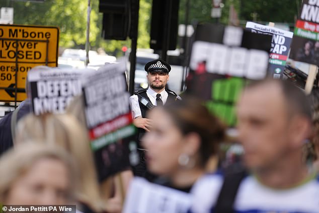 A police officer is seen among supporters of Kneecap's Liam Og O Hannaidh at court today