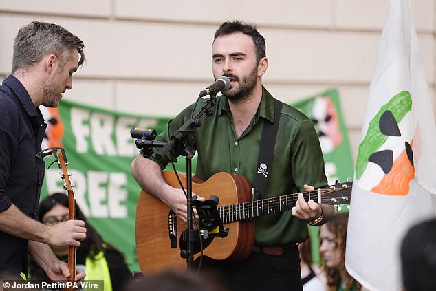 A guitarist performs among supporters of Kneecap's Liam Og O Hannaidh outside court today