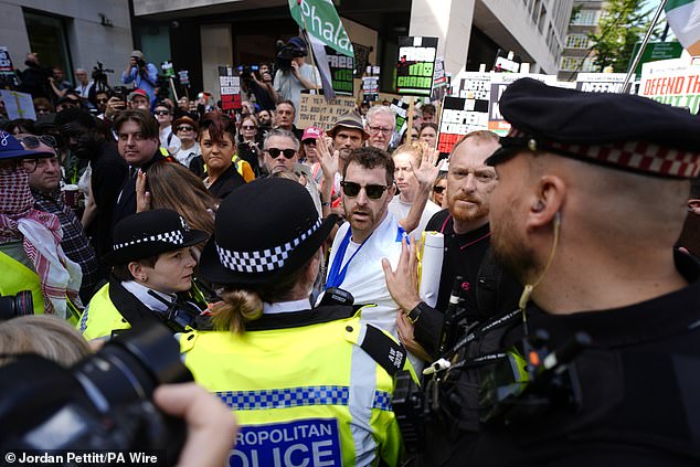 Police officers remove a counter-protester from the middle of supporters of Kneecap today