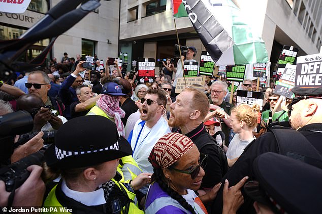 Police officers remove a counter-protester from the middle of supporters of Kneecap today