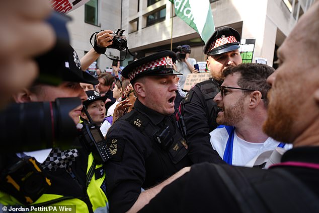 Police officers remove a counter-protester from the middle of supporters of Kneecap today