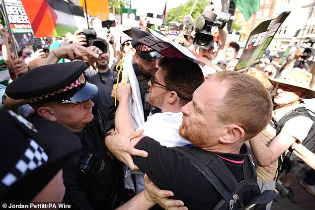 Police officers remove a counter-protester from the middle of supporters of Kneecap today
