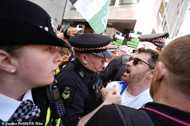 Police officers remove a counter-protester from the middle of supporters of Kneecap today