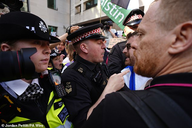 Police officers remove a counter-protester from the middle of supporters of Kneecap today