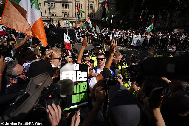 Police officers speak to counter-protesters (centre) in the middle of supporters of Kneecap