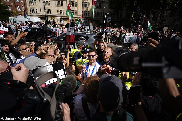 Police officers speak to counter-protesters (centre) in the middle of supporters of Kneecap