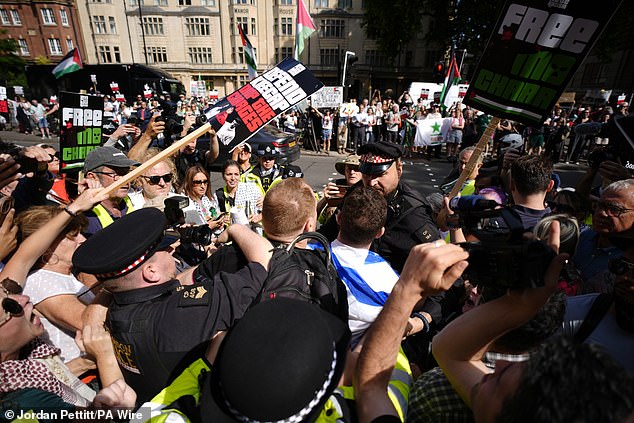 Police officers remove a counter-protester from the middle of supporters of Kneecap today