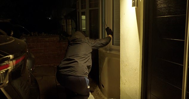 One of the thieves is pictured holding the amplifier outside the property during the staged theft