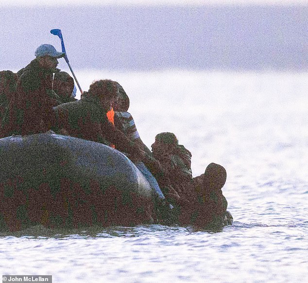 The man appeared to be lifted from the water with the help of other immigrants