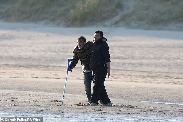 A bearded middle-aged man, who could only hobble towards the waves aided by a friend