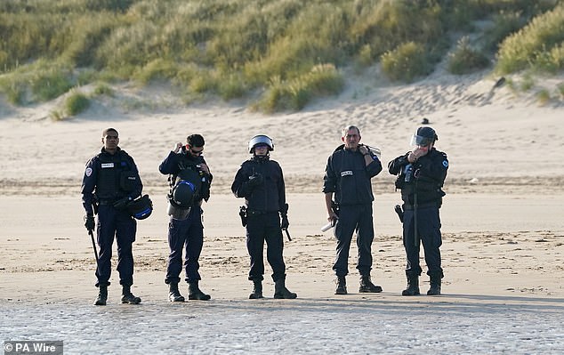 Currently, they are barred from intercepting any boat once it is in the water (pictured French authorities seen on a beach in Gravelines as they watch people thought to be migrants wade through the sea to board a small boat leaving the beach)