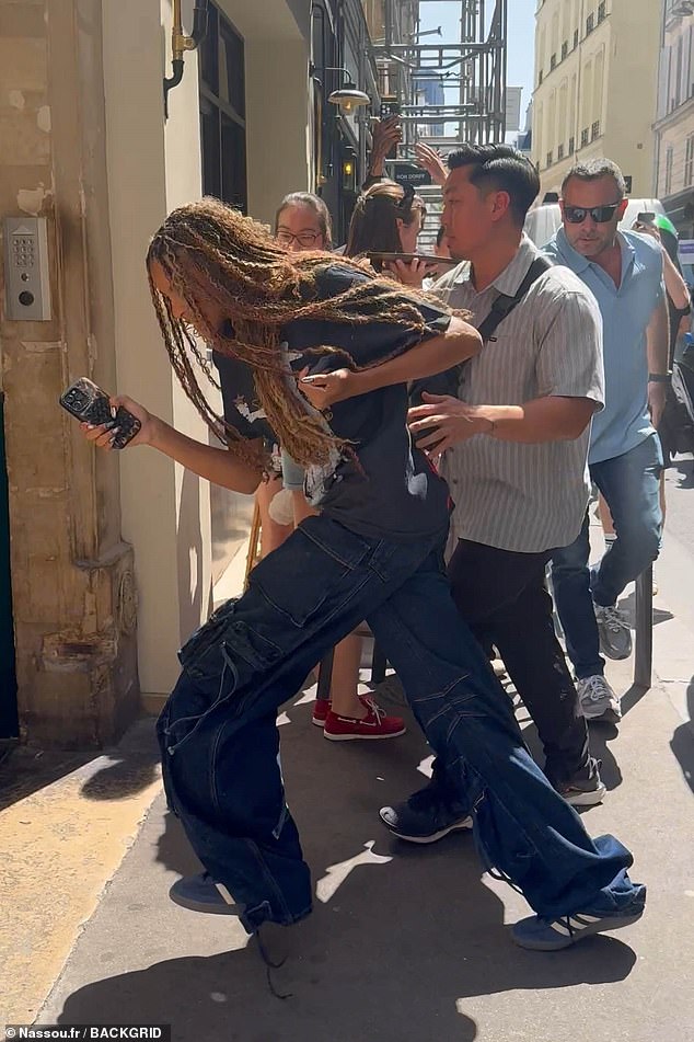 Blue sported dark denim baggy jeans and an oversized grey t-shirt with a pair of blue Adidas trainers