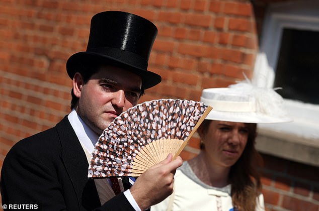 This racegoer keeps cool in the heat with a handy fan when attending Royal Ascot