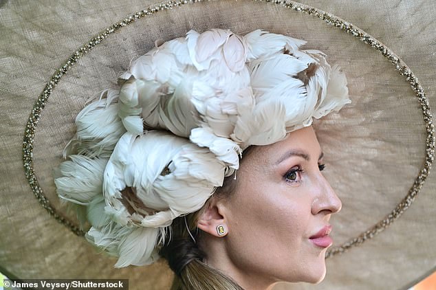 Hat's glamorous! A racegoer sports a statement headpiece complete with feathers and beads