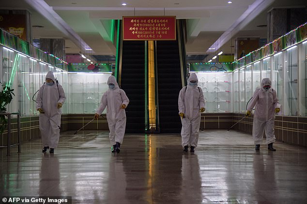 Pictured: North Korean health workers in hazmat suits disinfect inside the Pyongyang Department Store No. 1 in December 2020. After claiming to have kept the virus at bay, state media said that more than 350,000 people have now shown fever symptoms since late April