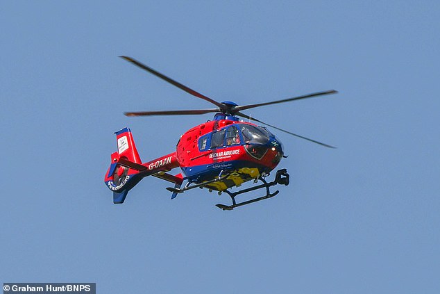 An Air Ambulance helicopter arrives to give assistance to the casualty on the beach beneath the cliffs of Swyre Head