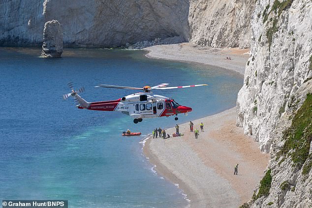 A Coastguard helicopter hovers above Durdle Door Beach after receiving reports of a woman in need of urgent medical attention