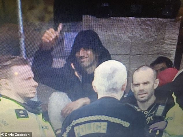 A migrant grins at the camera and offers a cheeky thumbs up from the back of a lorry