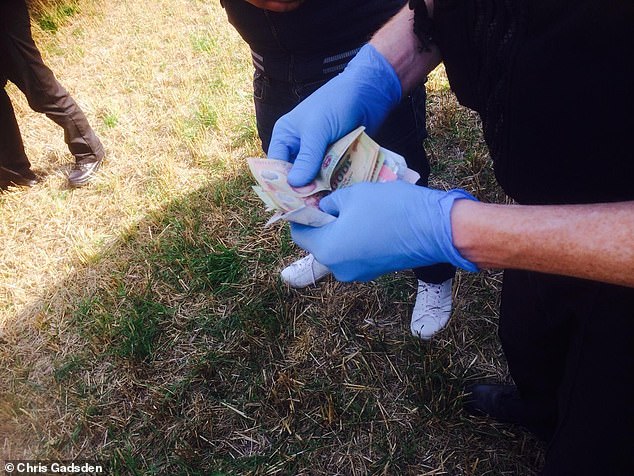 A police officer rifles through a huge bundle of money taken from one migrant