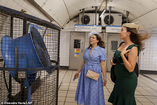Two women travelling to Ladies Day at Royal Ascot cool off on the London Underground yesterday