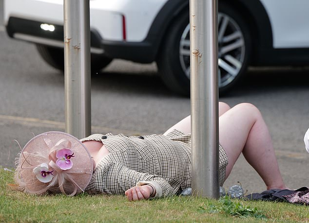 A lady takes a minute to recover and lie on the grass outside the venue