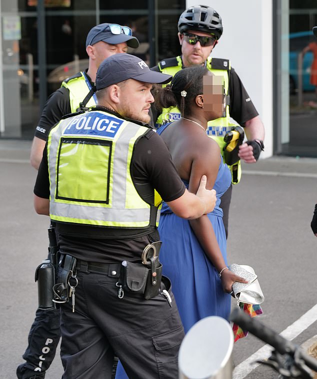 One woman is escorted away by police on the second day of the Ascot races